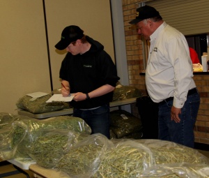 A man and another man standing next to bags of marijuana.