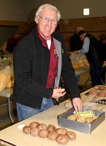 A man standing at a table with bread.