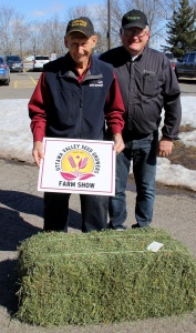 A man standing next to a pile of hay.