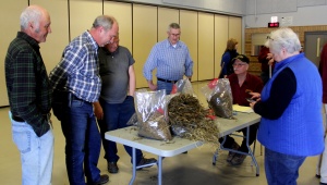 A group of people standing around tables with bags.