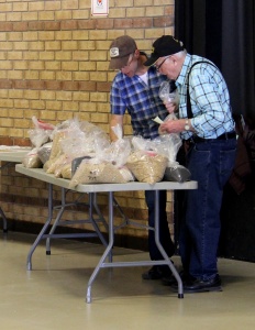 Two men standing at a table with bags of food.