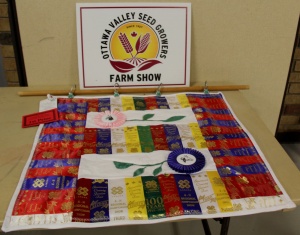 A table with ribbons and a sign for the ottawa valley seed growers farm show.