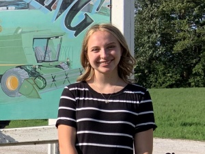 A young woman standing in front of a painting.