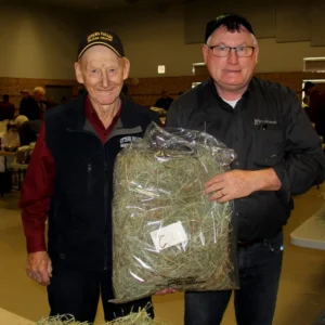 Two men holding a bag of hay.